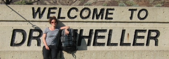 'Welcome to Drum Heller' sign, but with Dr Heller blocking the 'um' in 'Drum' to spell out 'Welcome to Dr Heller'